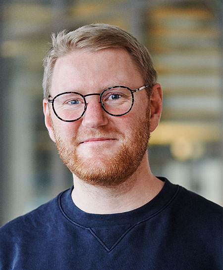 Ein Mann mit Brille und Bart, der in die Kamera lächelt.