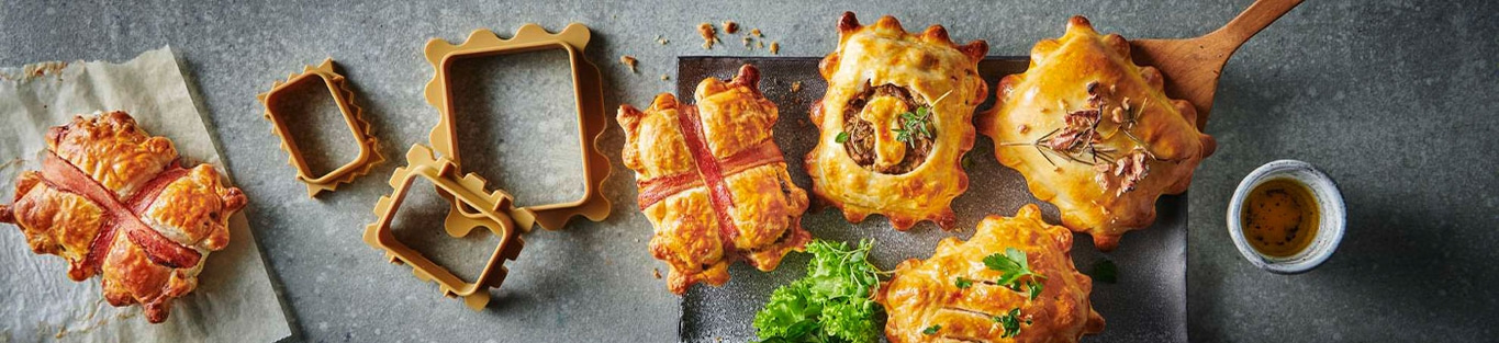 Gebäck mit Speck, Rahmen, Kräutern und Soße auf grauem Hintergrund.