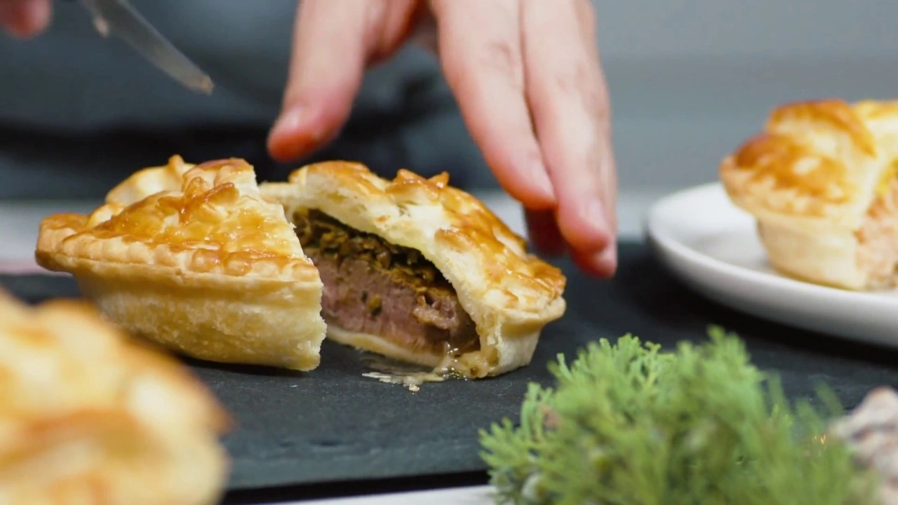 Une tourte à la viande est coupée avec un couteau pour révéler l'intérieur.
