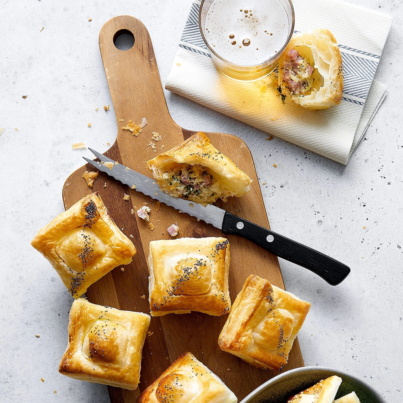 Köstliche Pasteten auf einem Holzbrett mit Bier und Messer.