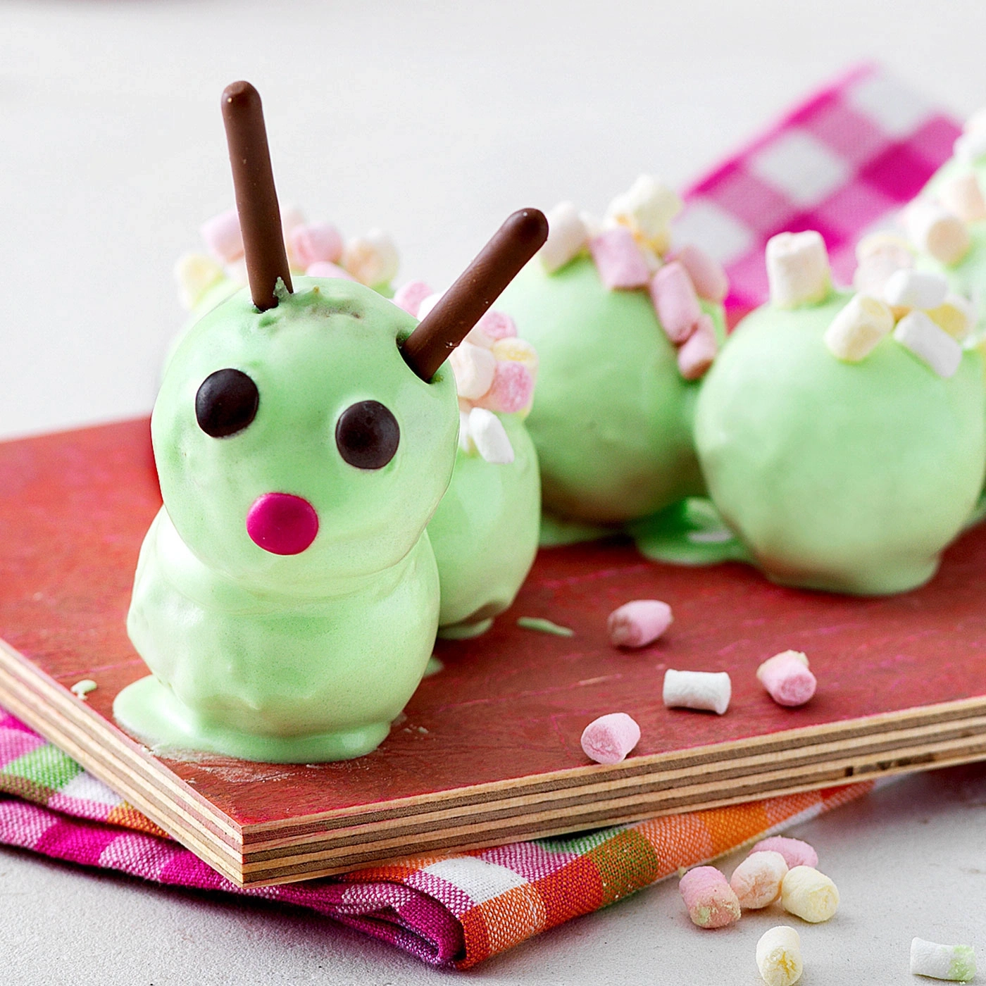 Grüne Raupen-Kuchen mit Schokoladen-Antennen und Marshmallows auf Holzbrett