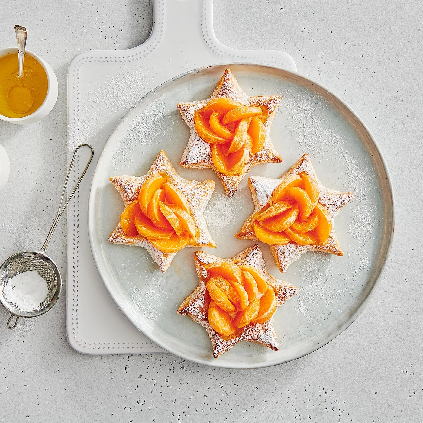 Pâtisseries en forme d'étoile avec mandarines, assiette, sucre glace.