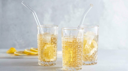 Trois verres de boisson avec glaçons et tranches de citron, avec pailles.