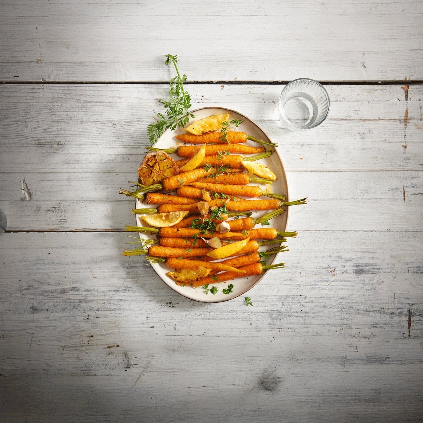 Carottes rôties sur une assiette avec citron et ail, verre d'eau