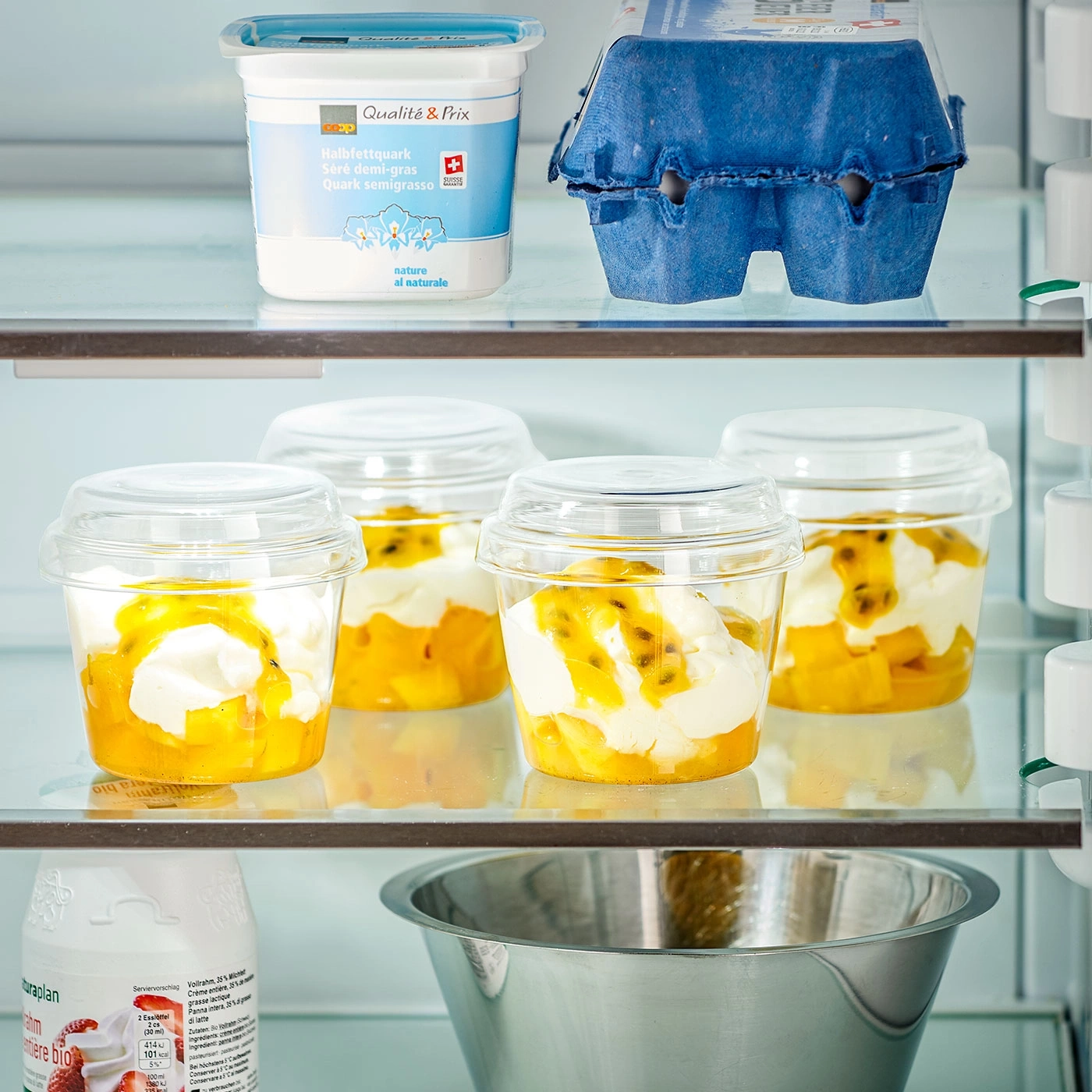 Kühlschrank mit Quark, Eiern, Dessertbechern und einer Schüssel.