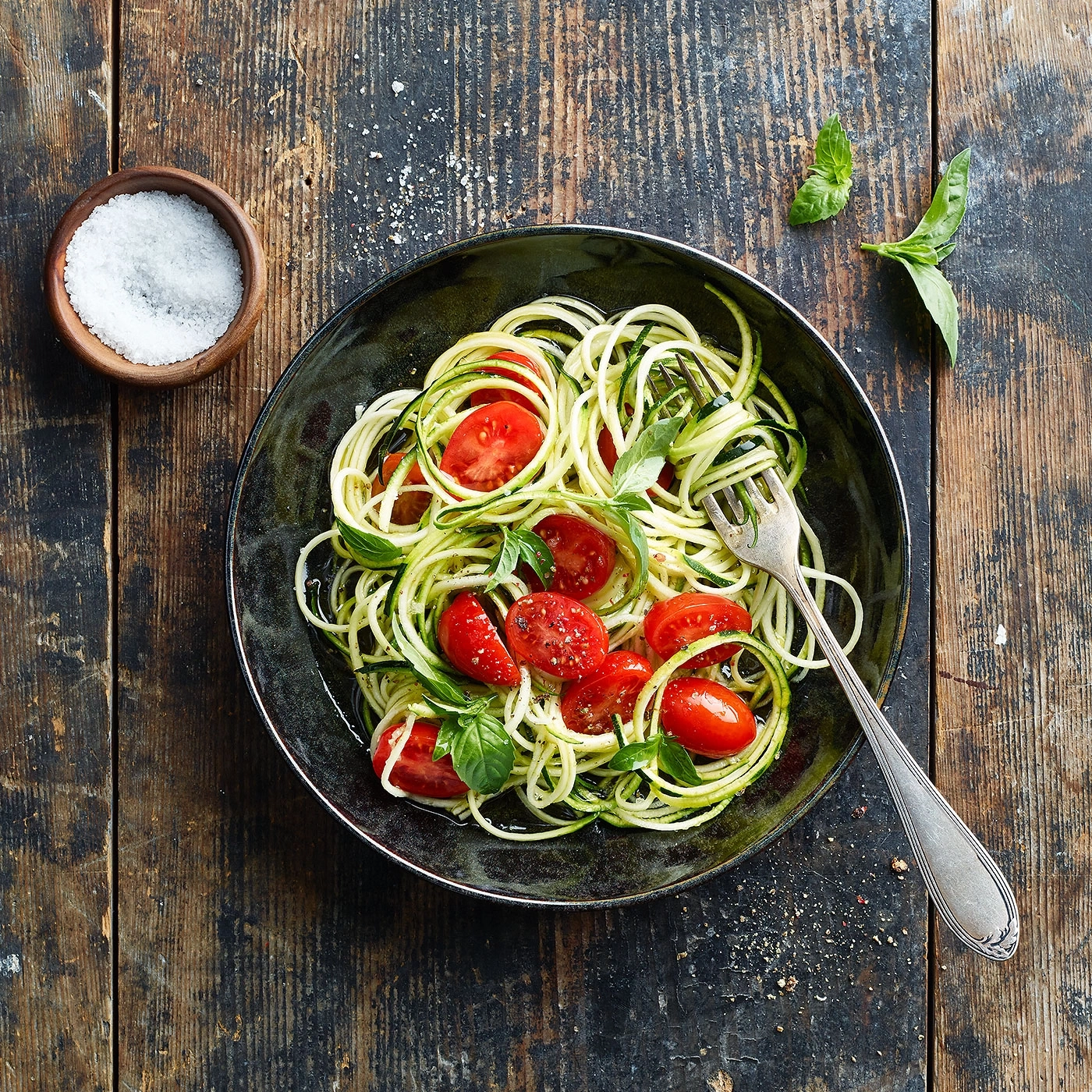 Nouilles de courgettes avec tomates et basilic sur une table en bois
