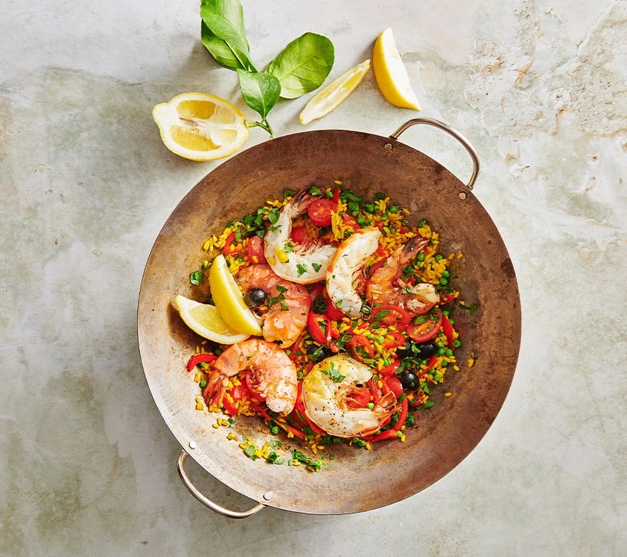 Paella mit Garnelen, Zitrone und Gemüse in einer Pfanne
