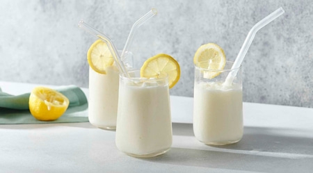 Trois verres de limonade avec pailles et tranches de citron, rafraîchissant et savoureux.