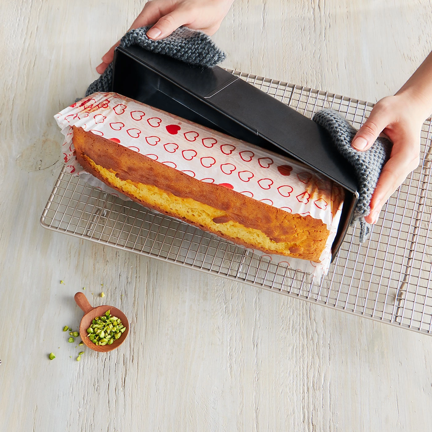 Kuchen wird aus der Form genommen, auf einem Rost mit Pistazien serviert.