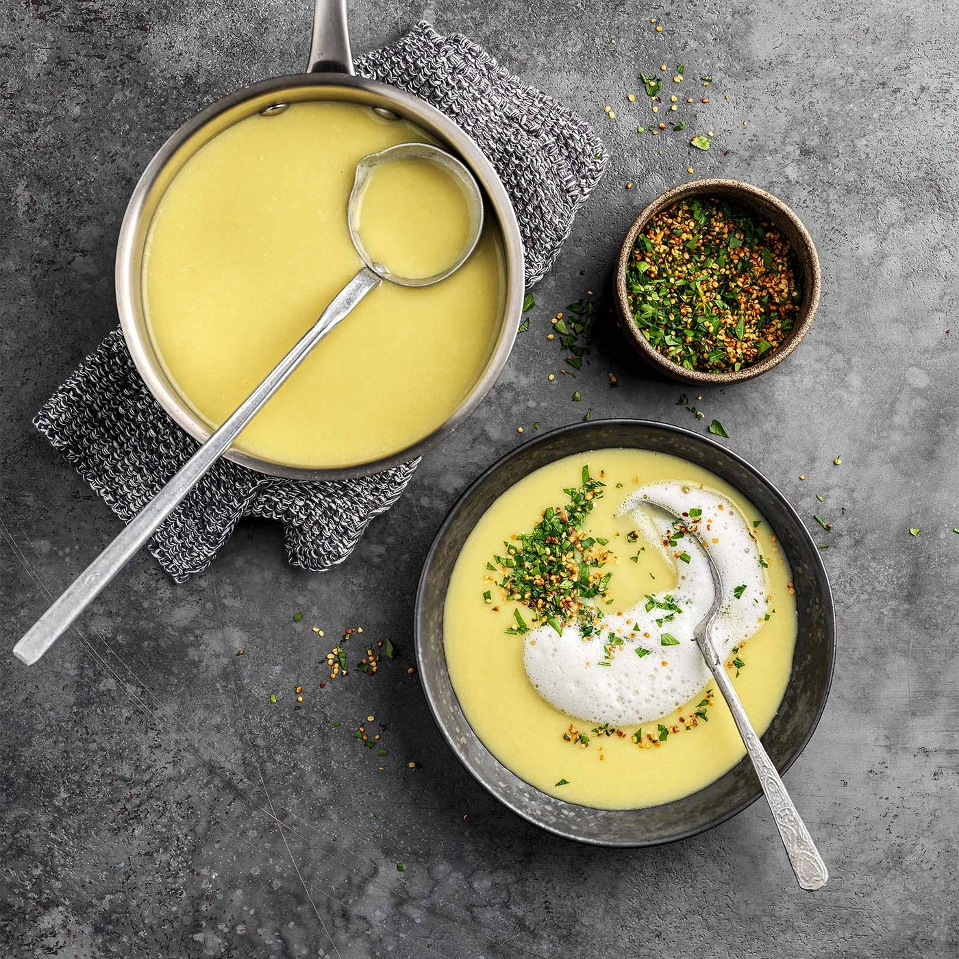 Suppe mit Schaum, Kräutern und Gewürzen, serviert in einer Schüssel und einem Topf.