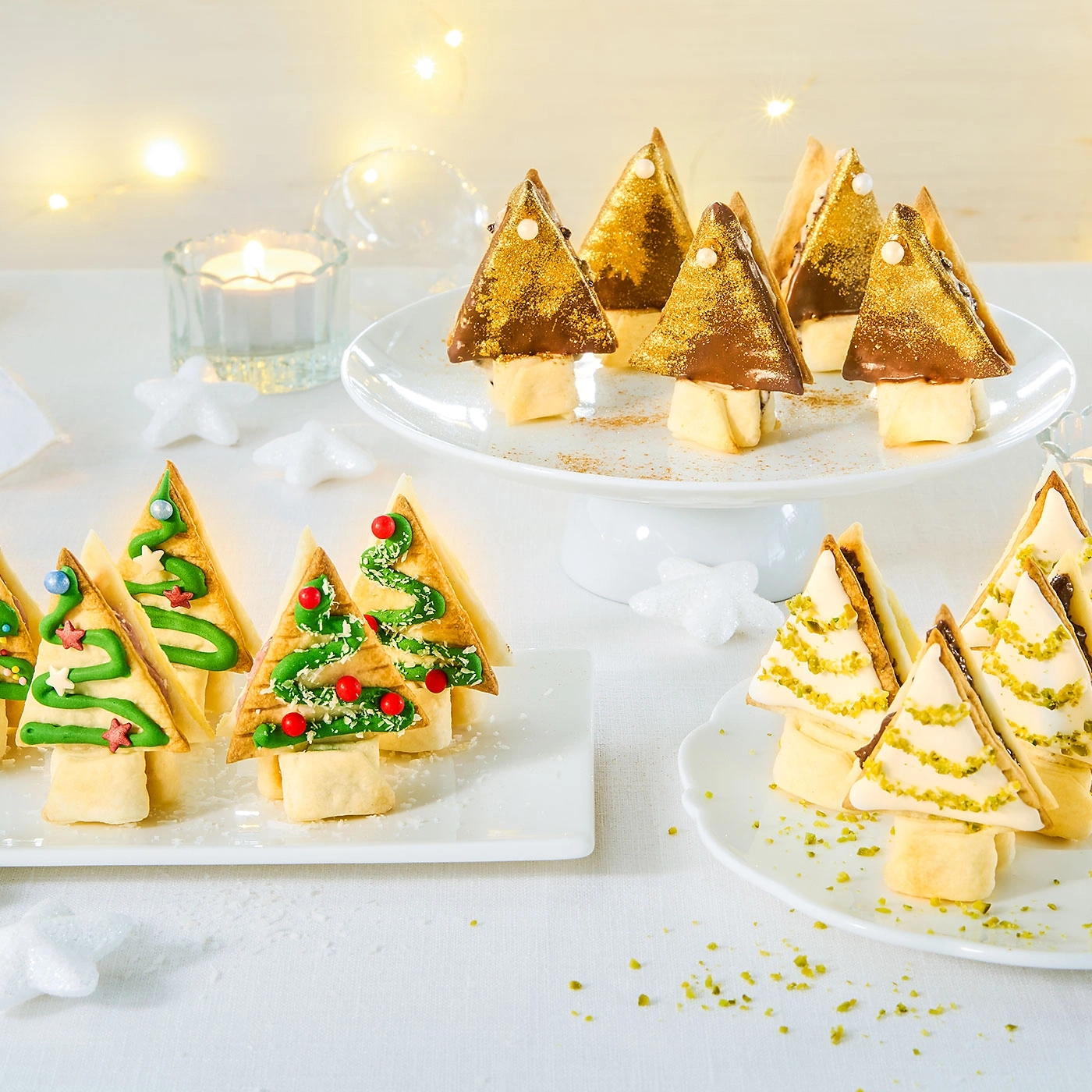 Weihnachtliche Leckereien: Baumförmige Gebäckstücke mit Dekoration auf Tellern.