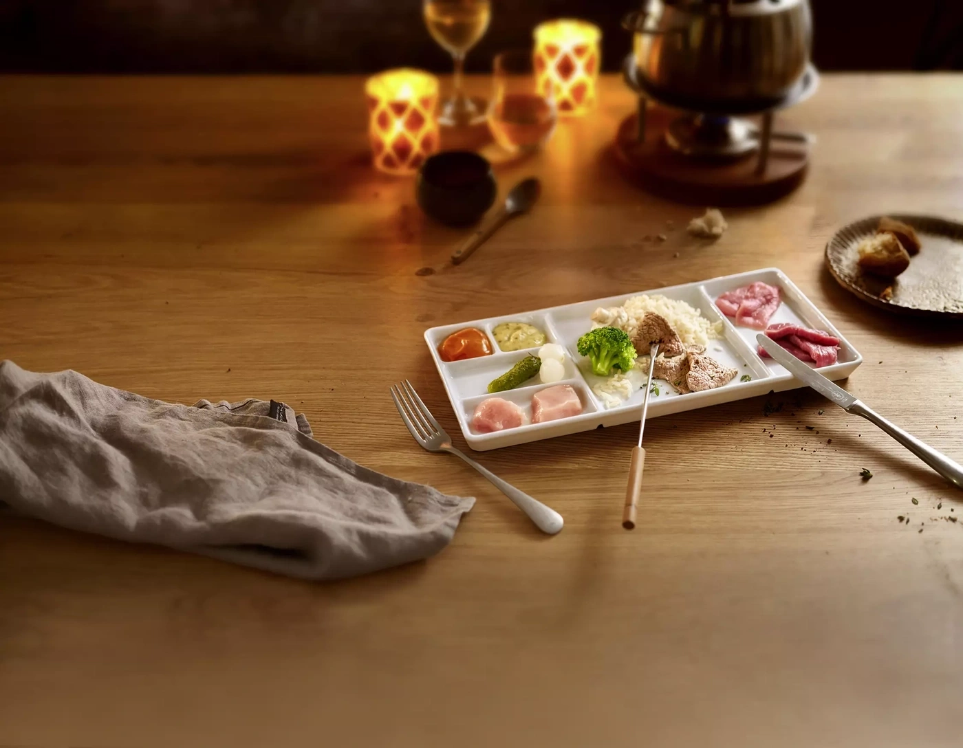 Fondue avec viande, légumes et accompagnements sur table en bois
