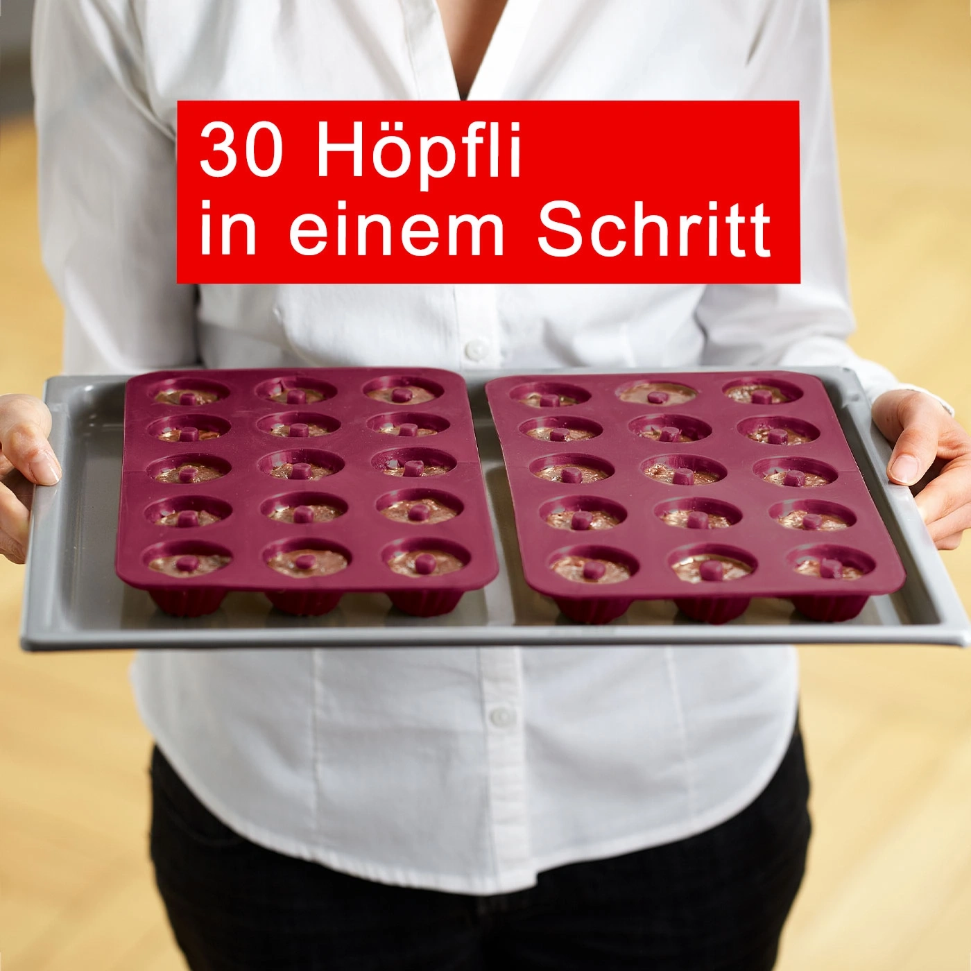 Personne tenant une plaque de cuisson avec 30 Höpfli en une étape. Texte rouge.