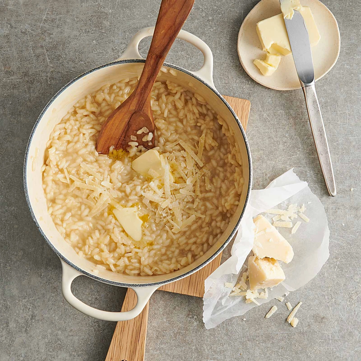 Risotto mit Butter und Käse in einem Topf auf einem Holzbrett