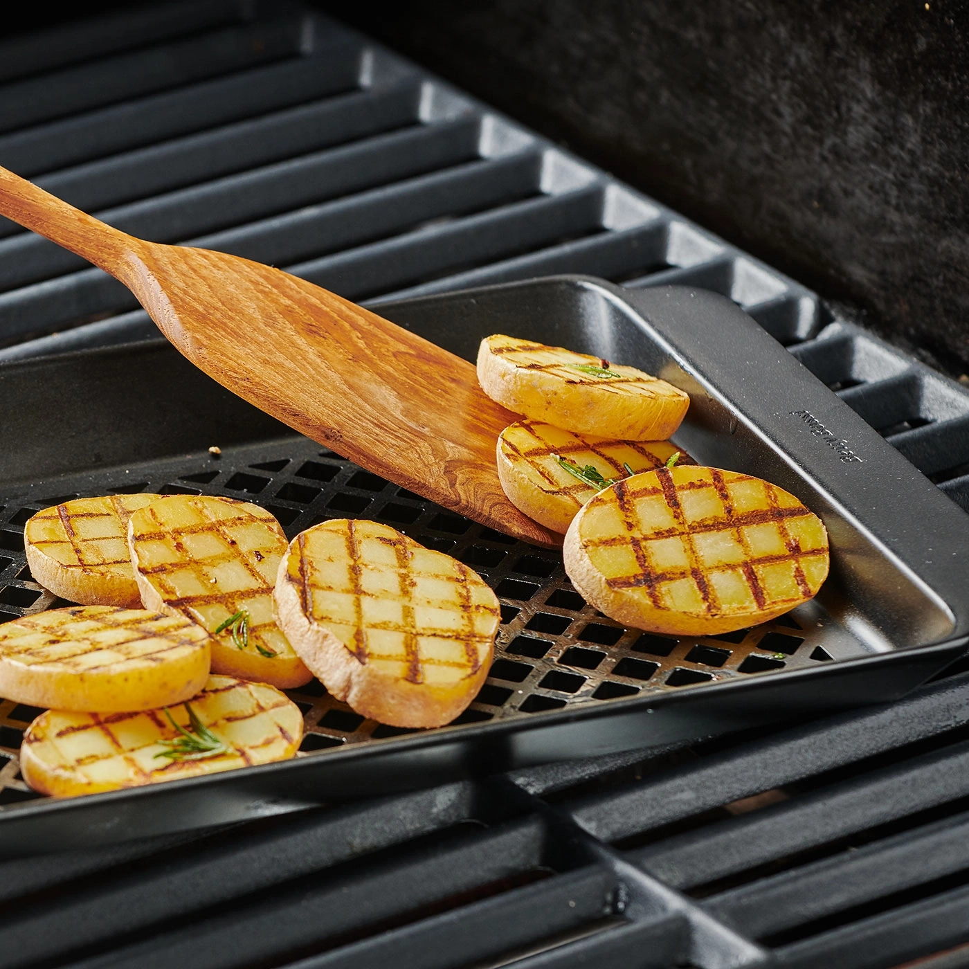 Tranches de pommes de terre grillées sur une grille avec une spatule en bois et une poêle