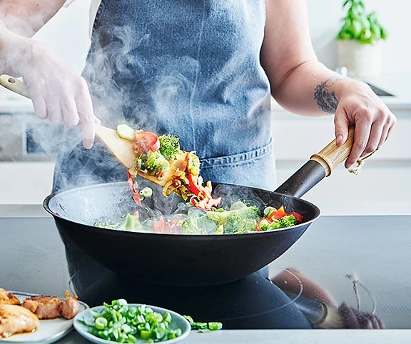 Kochen in der Pfanne mit Gemüse, Dampf und Kochlöffel. Kochen in der Küche.
