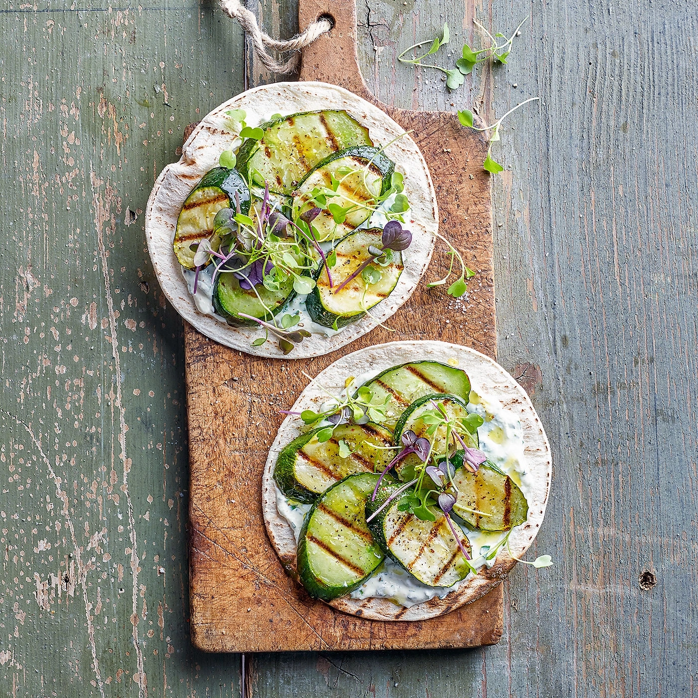 Tacos de courgettes grillées sur planche de bois, herbes et sauce