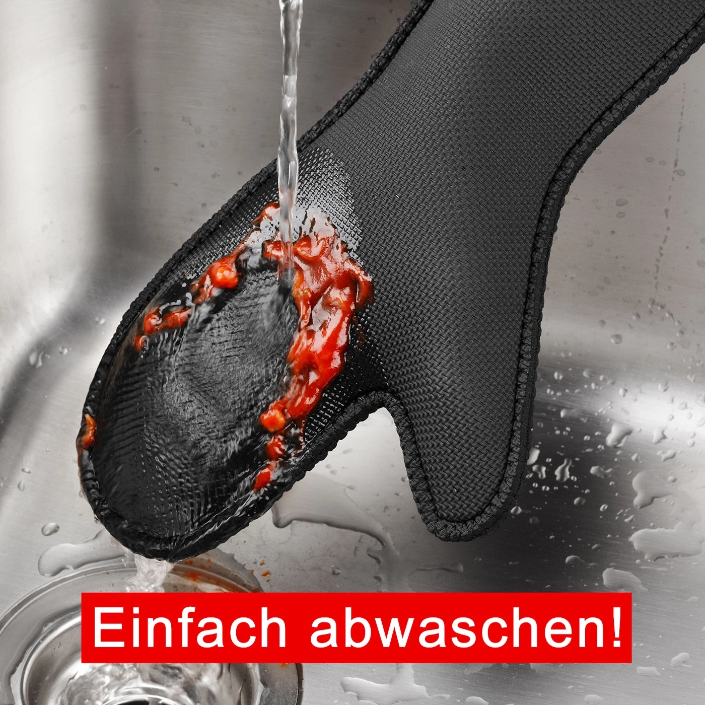 Schwarzer Ofenhandschuh wird mit Wasser und Tomatensoße gereinigt. Einfach abwaschen!