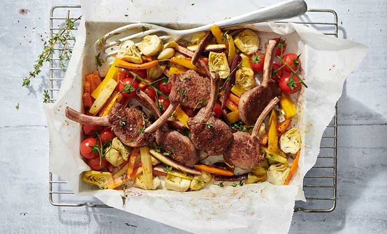 Côtelettes d'agneau rôties avec légumes dans un plat à four sur une grille