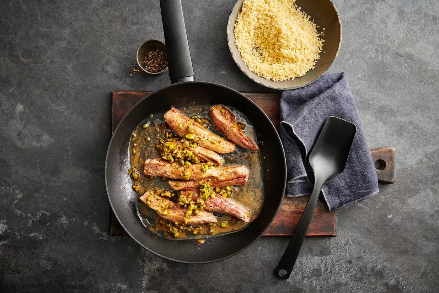 Lanières de viande aux pistaches dans une poêle à côté de couscous