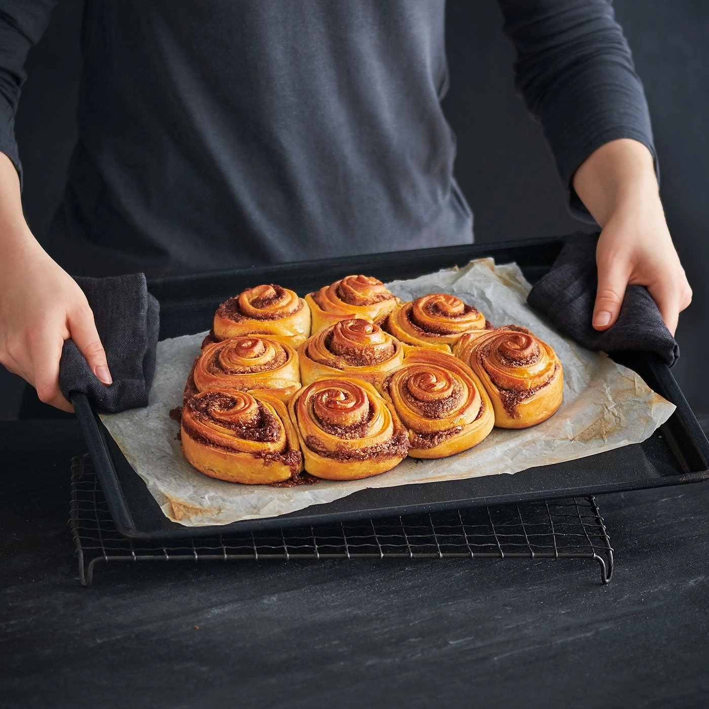 Person hält Backblech mit Zimtschnecken, Nahaufnahme, Essen, Backen, Küche