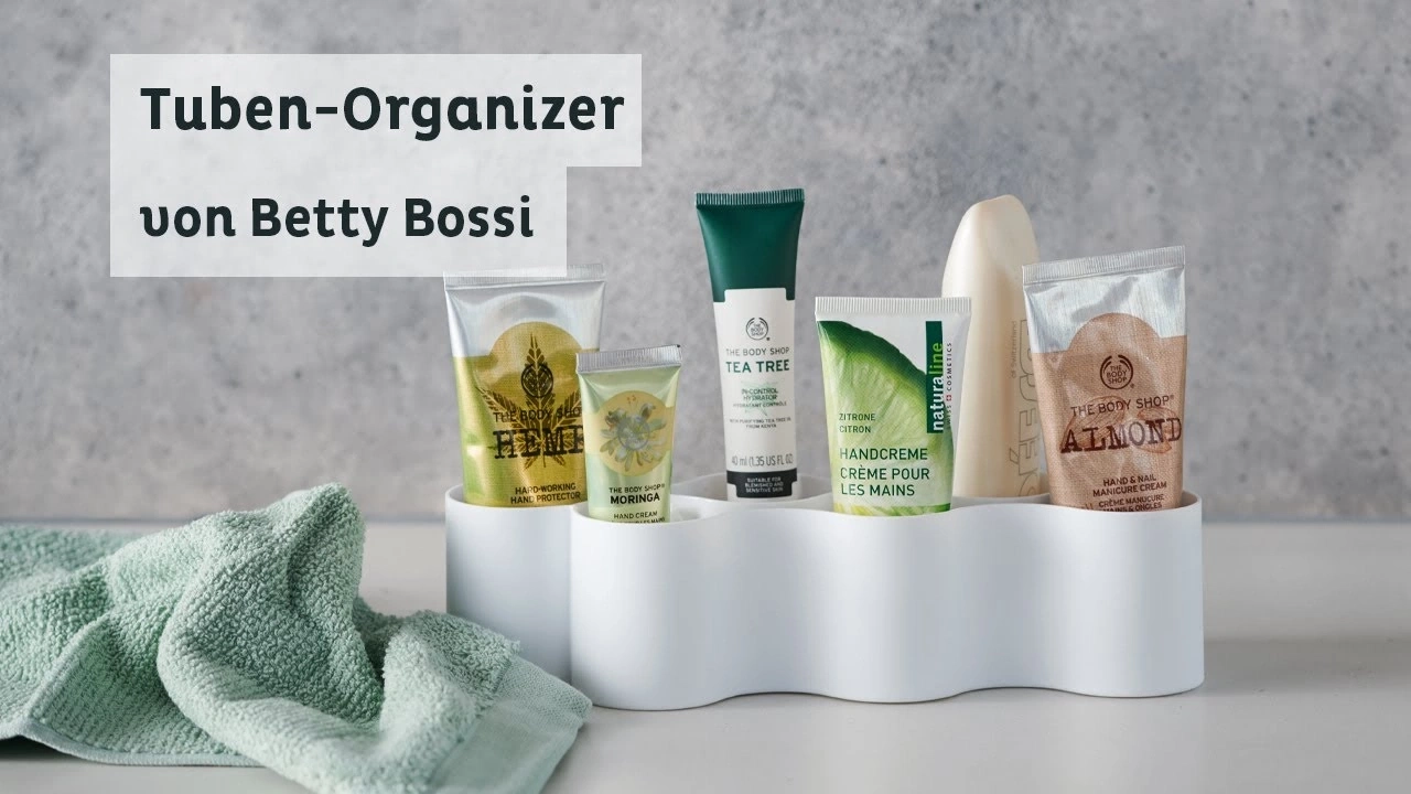 Organisateur de tubes avec crèmes pour les mains et une serviette verte, par Betty Bossi.