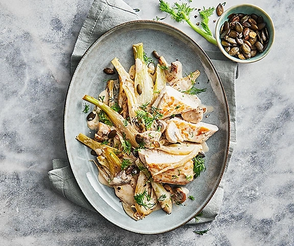Hühnchen-Gericht mit Fenchel, Pilzen und Samen auf einem Teller, Nahaufnahme.
