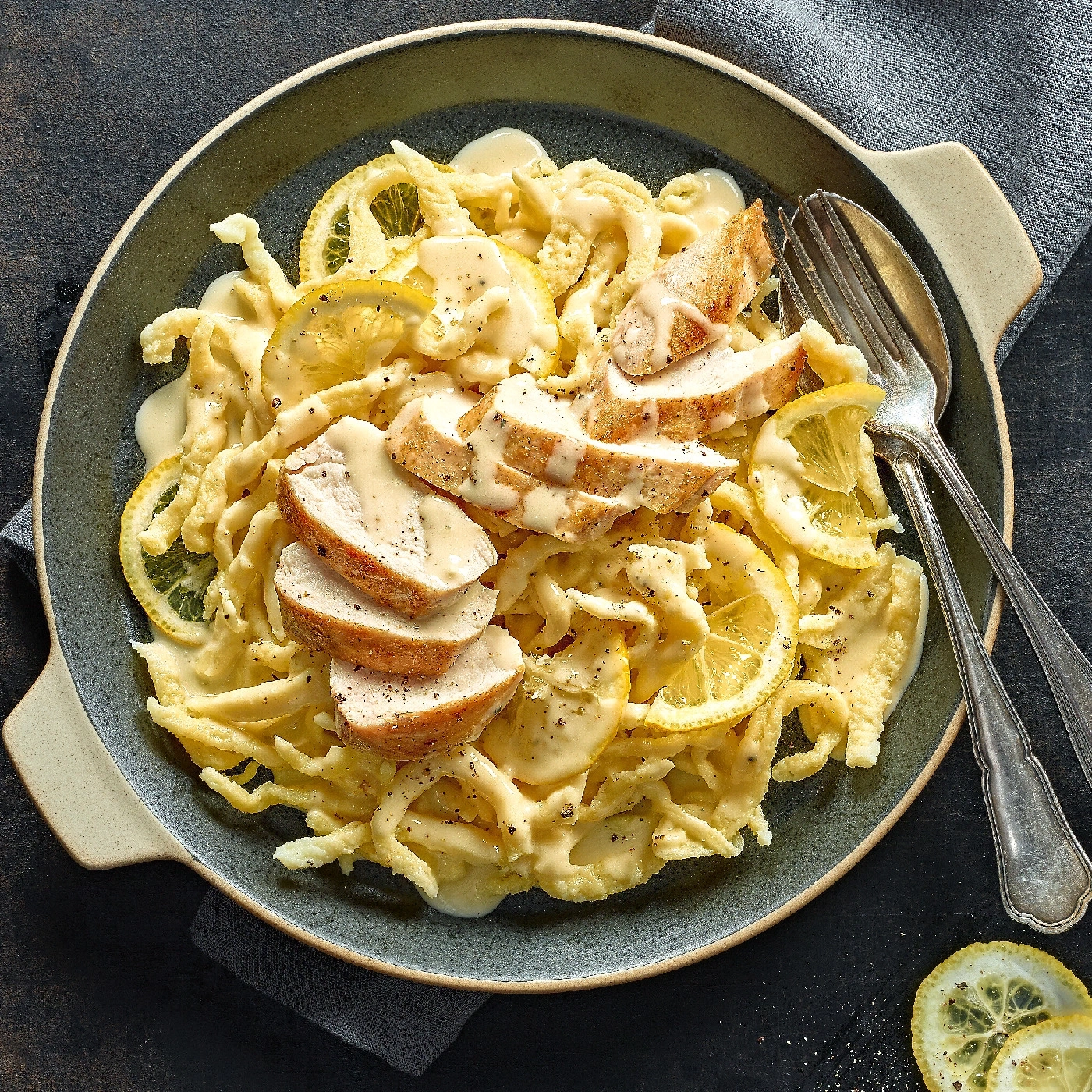 Hühnchen-Zitronen-Pasta mit Zitronenscheiben und Sauce in einer Schüssel.