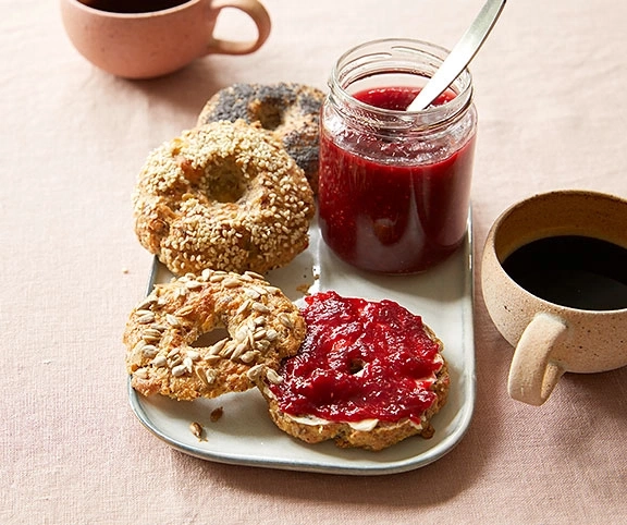 Frühstück mit Bagels, Marmelade und Kaffee auf einem Teller.
