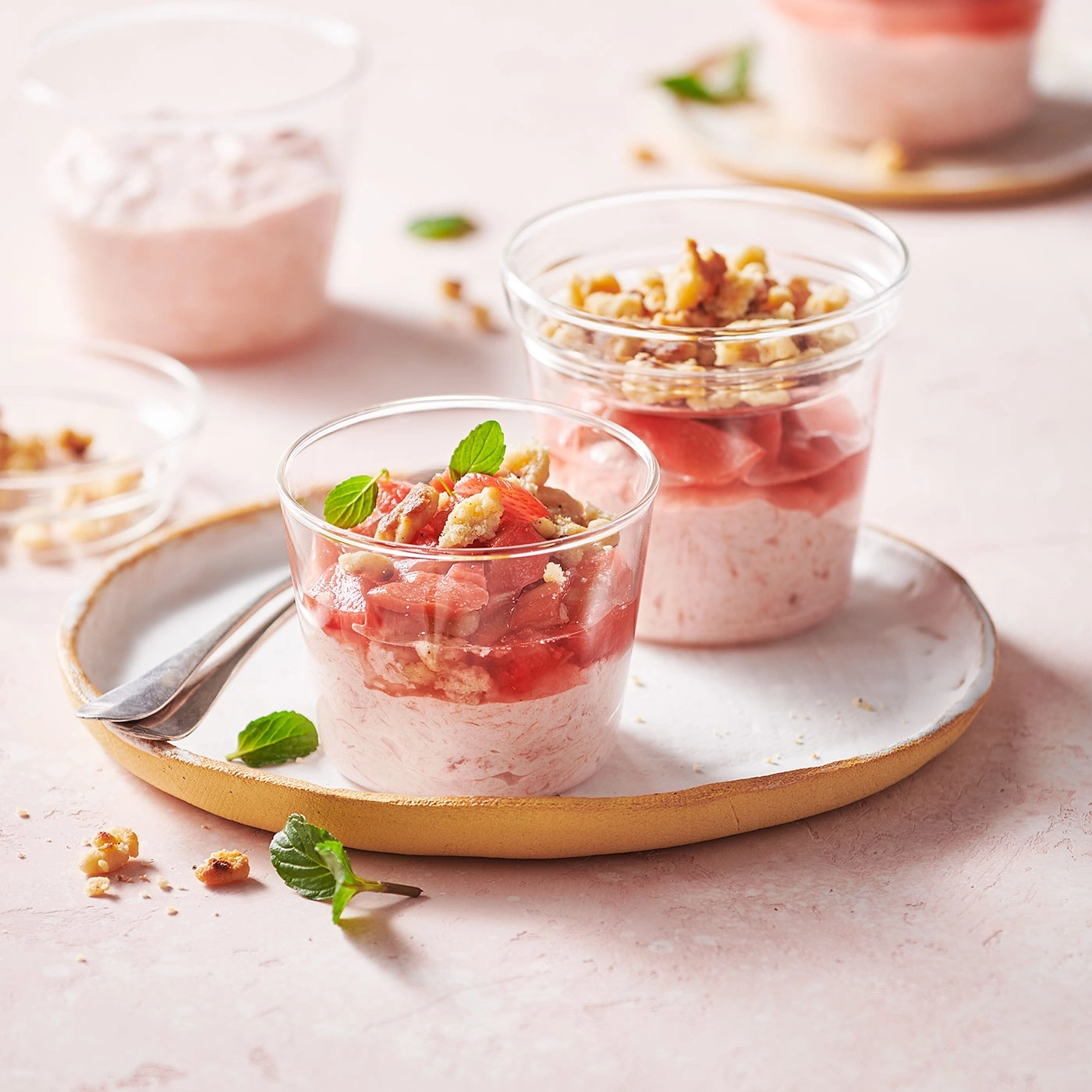 Dessert rose avec crème, rhubarbe et noix dans des verres sur une assiette.