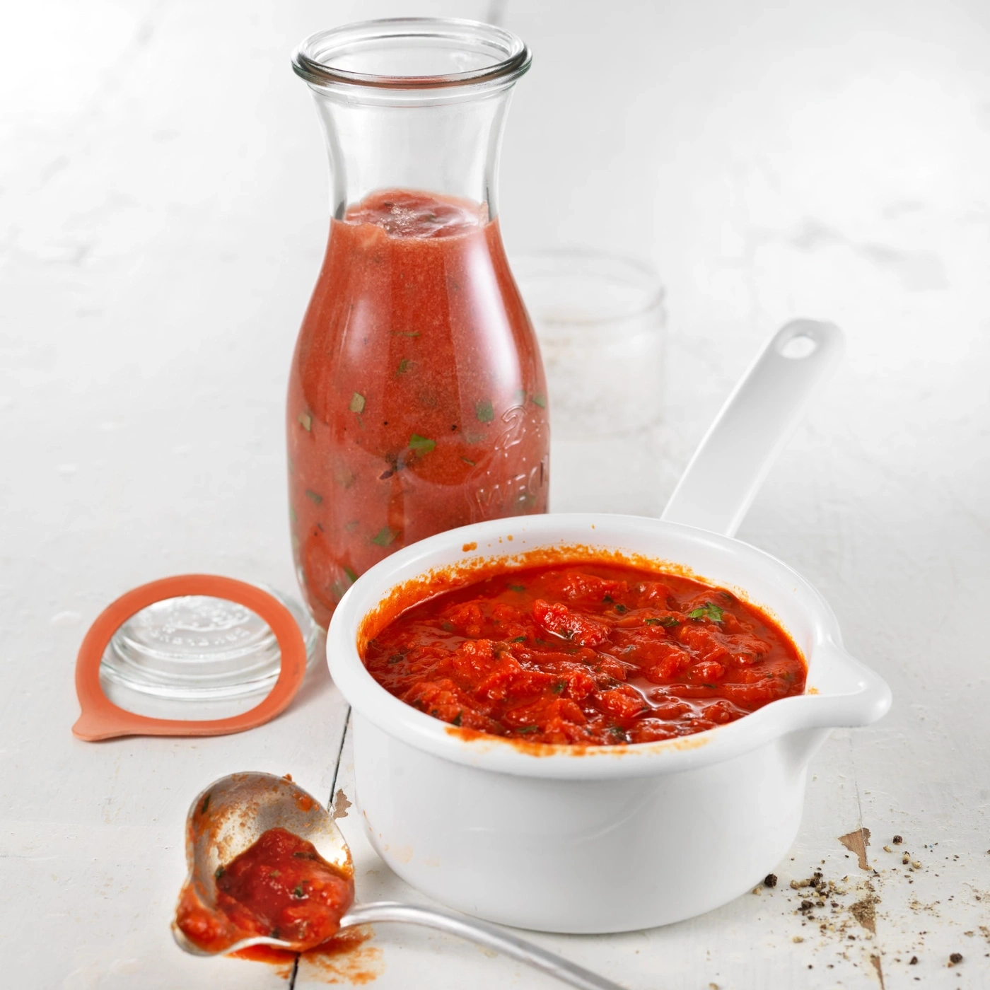 Sauce tomate dans une bouteille en verre et une casserole, avec une cuillère et un couvercle