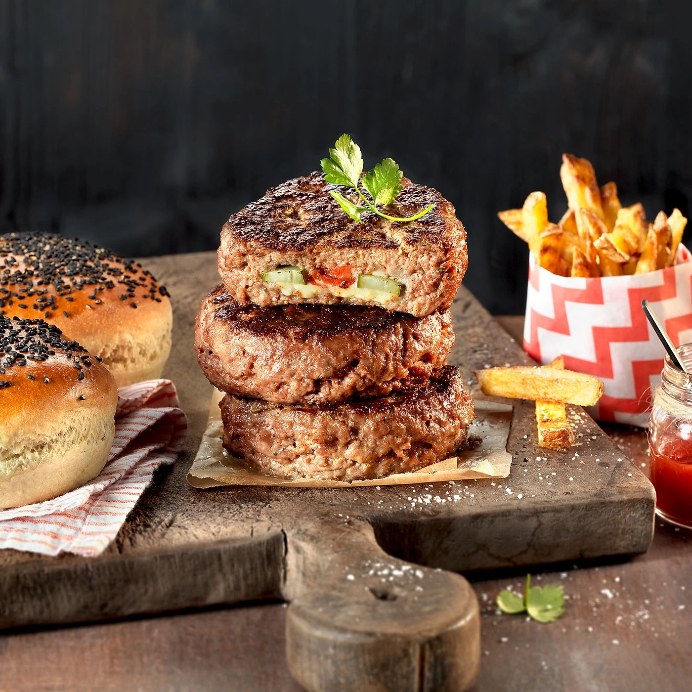 Tour de burgers avec frites et petits pains sur une planche en bois, délicieux