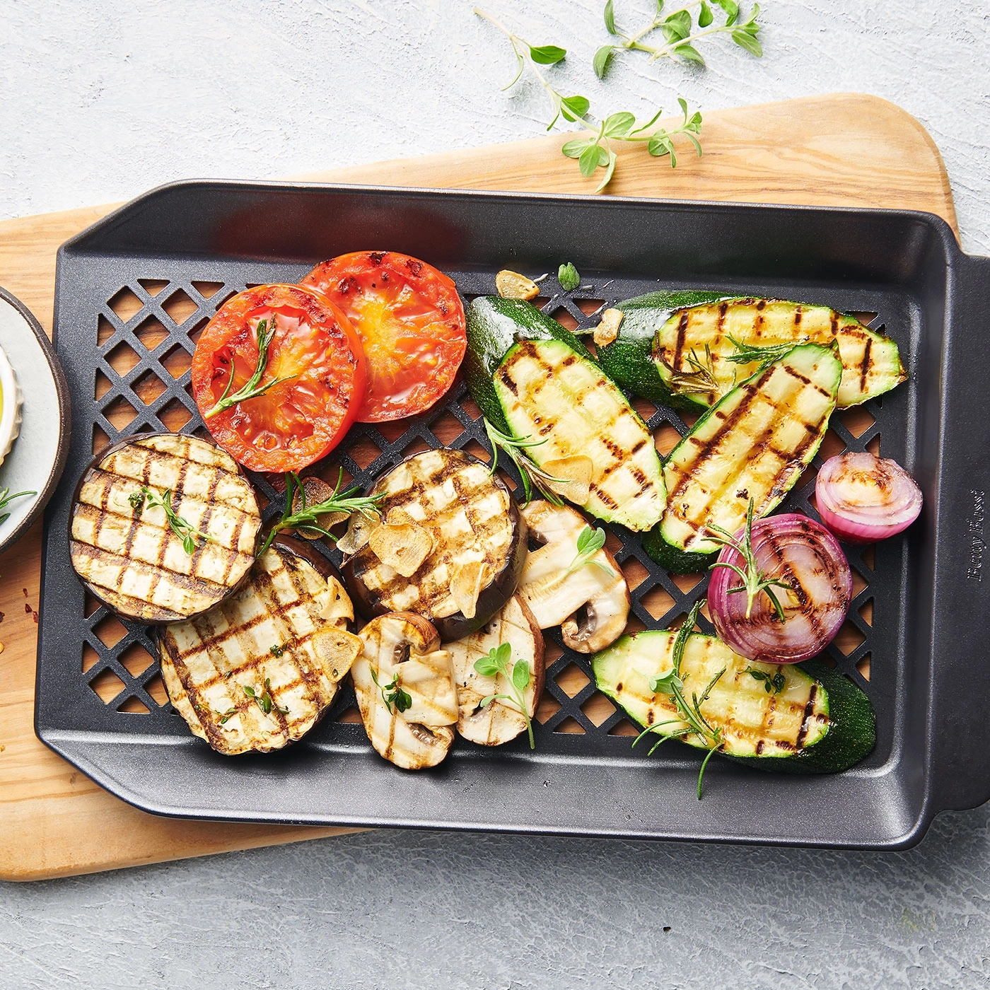 Légumes grillés sur un plateau. Tomates, courgettes, aubergines, oignons, ail et herbes aromatiques.