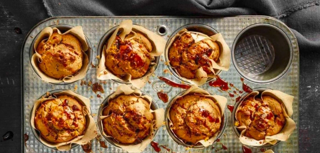 Muffins dans un moule à pâtisserie, doublés de papier et arrosés de sauce