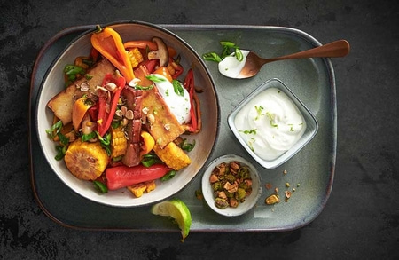 Plat de légumes avec tofu, maïs, sauce et citron vert sur un plateau