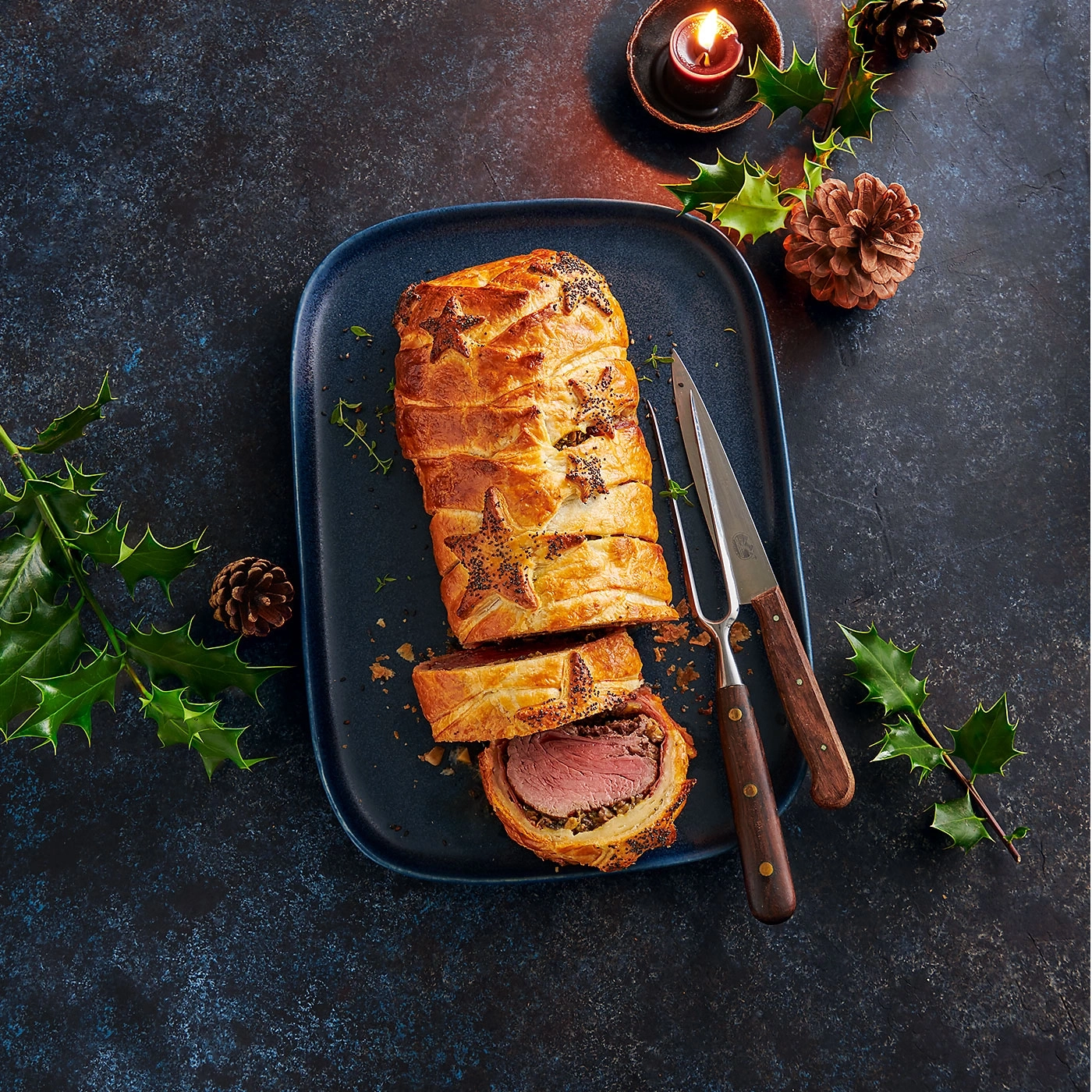 Festliches Gericht: Rinderfilet Wellington auf einem blauen Teller mit Dekoration.
