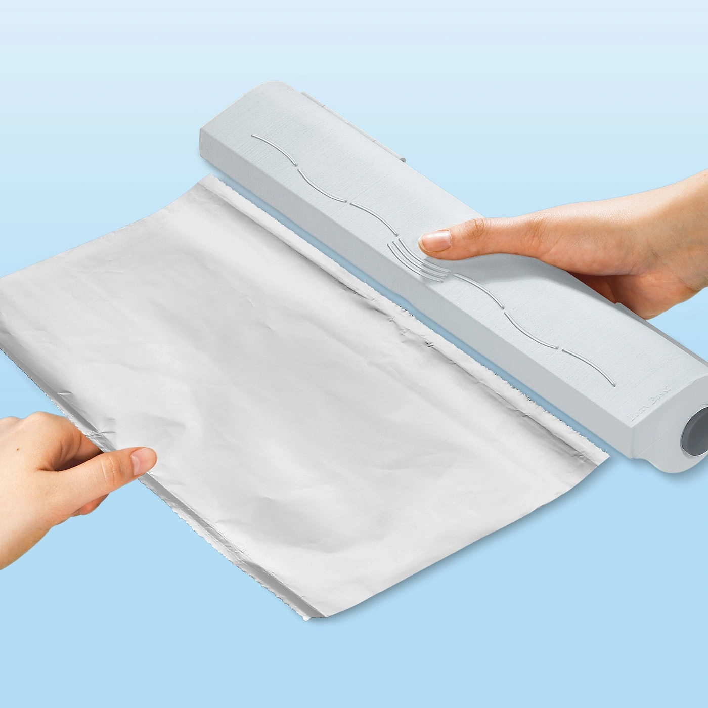 Du papier d'aluminium est coupé avec un appareil blanc sur fond bleu.