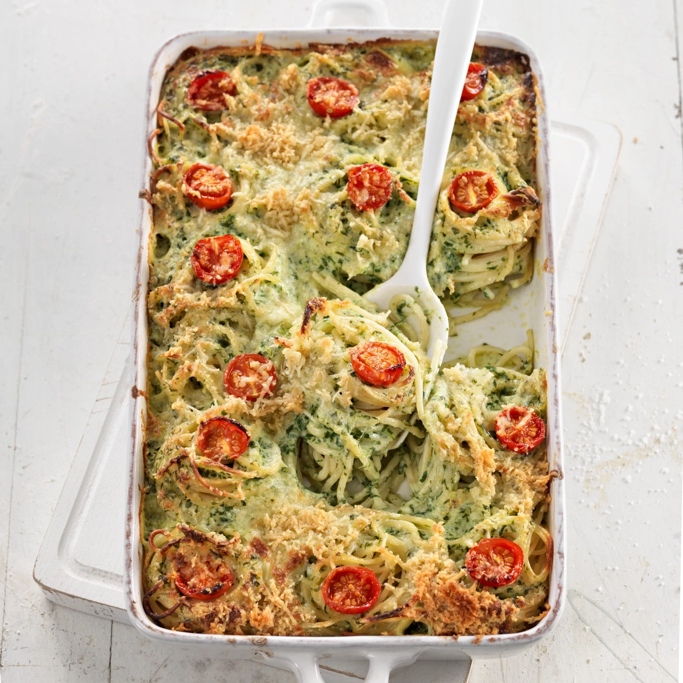Plat de pâtes, tomates et fromage dans un plat blanc sur une planche