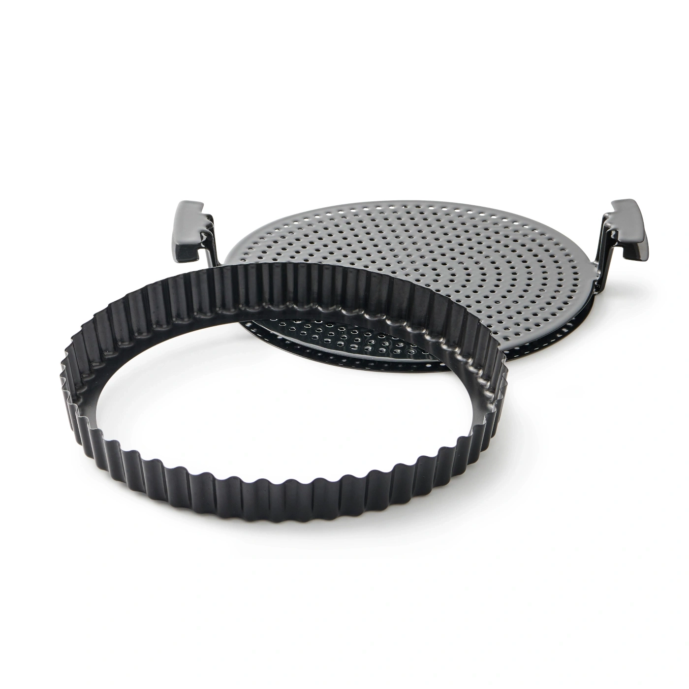 Moule à tarte noir avec bord ondulé et fond perforé sur fond blanc