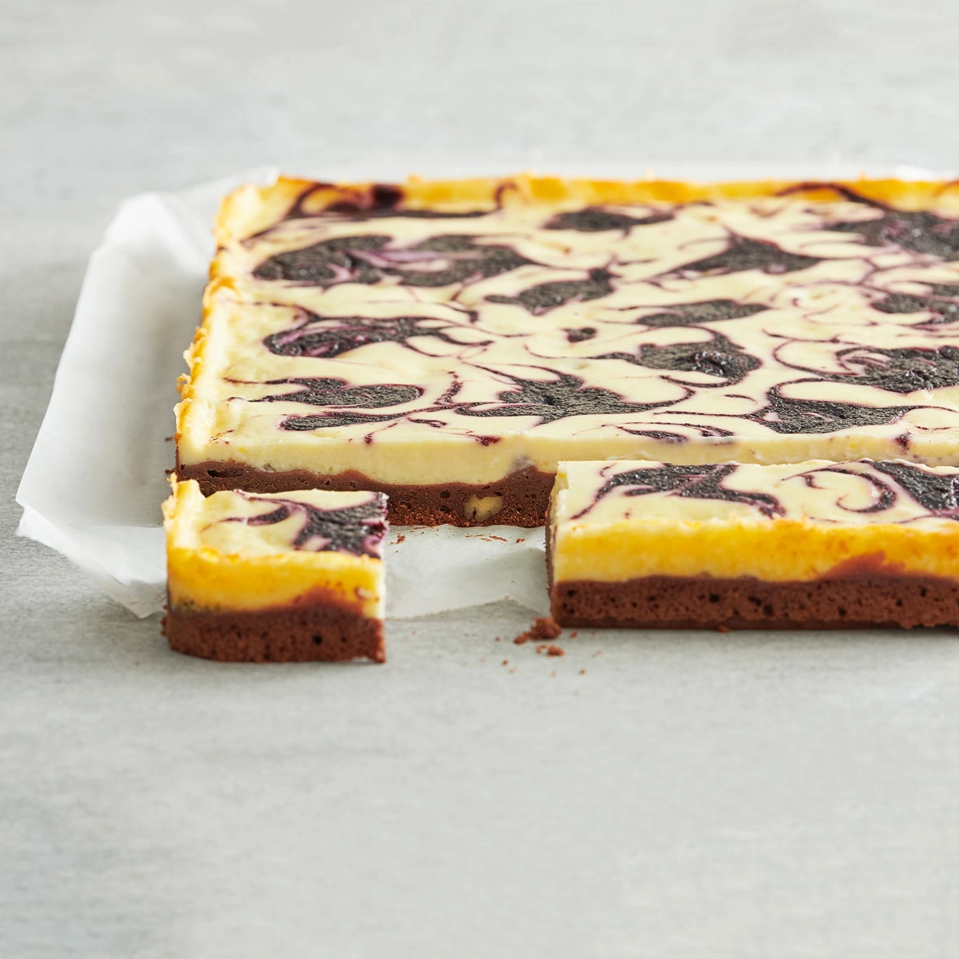 Kuchen mit Blaubeeren-Swirls, auf Backpapier, angeschnitten, Nahaufnahme