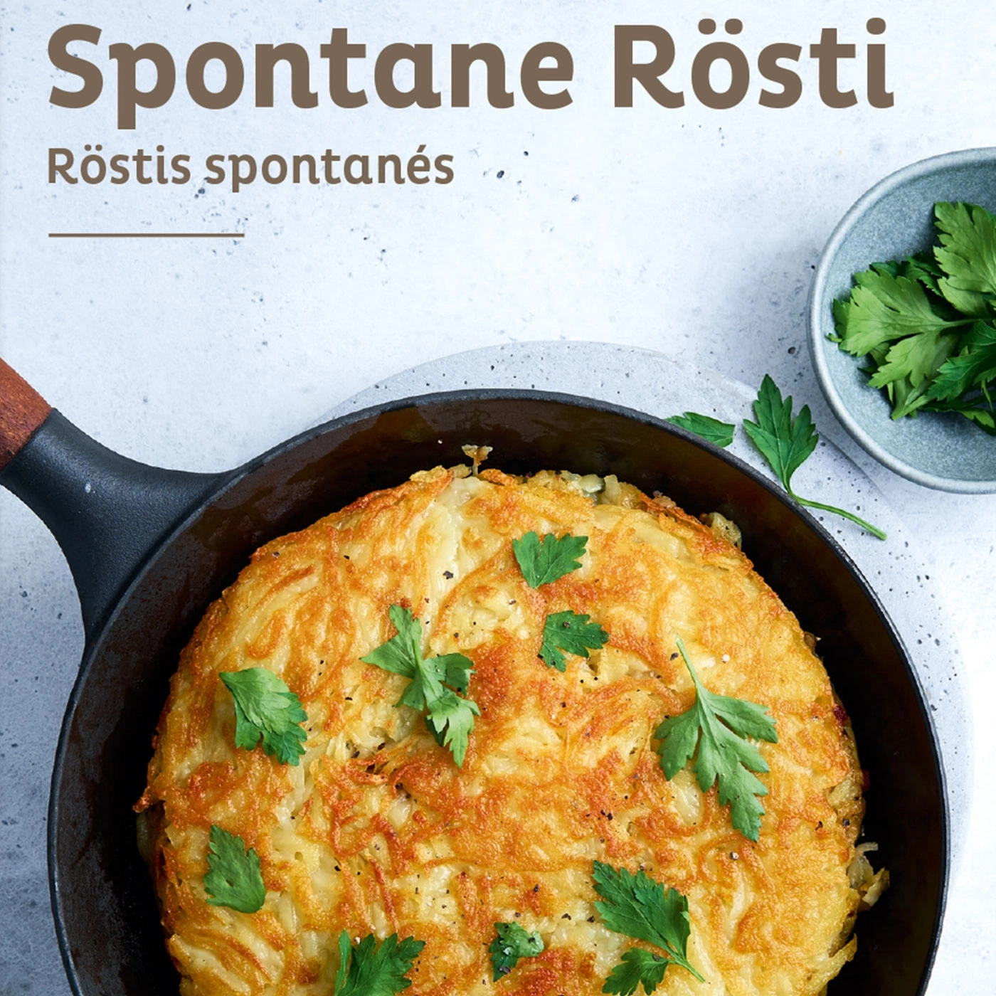 Knuspriges Rösti in der Pfanne, garniert mit Petersilie, auf hellem Hintergrund.