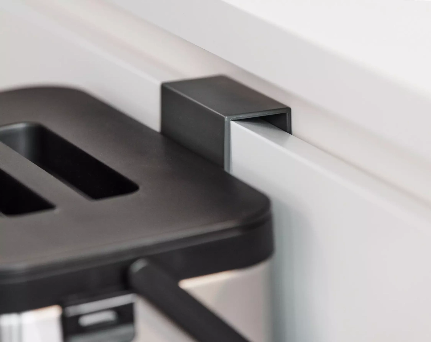 Gros plan d'un grille-pain noir à côté d'un mur blanc