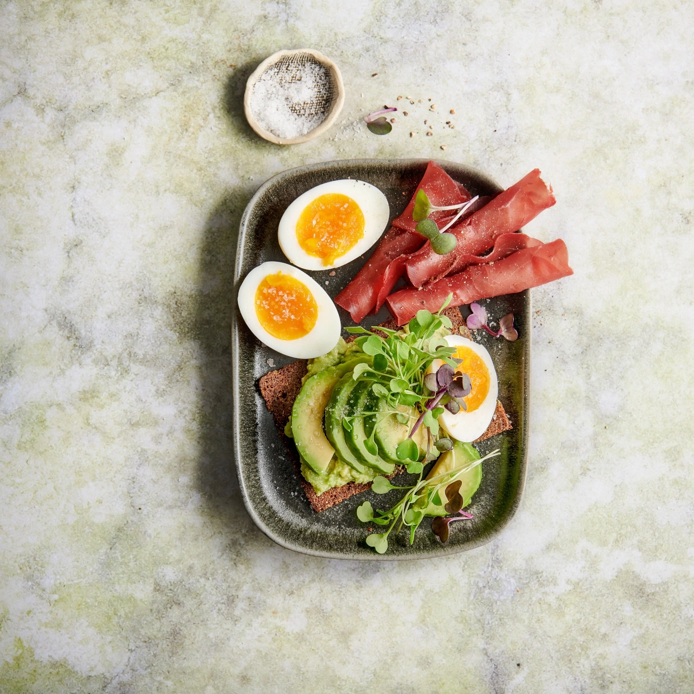 Toast à l'avocat avec des œufs et de la viande sur une assiette, gros plan