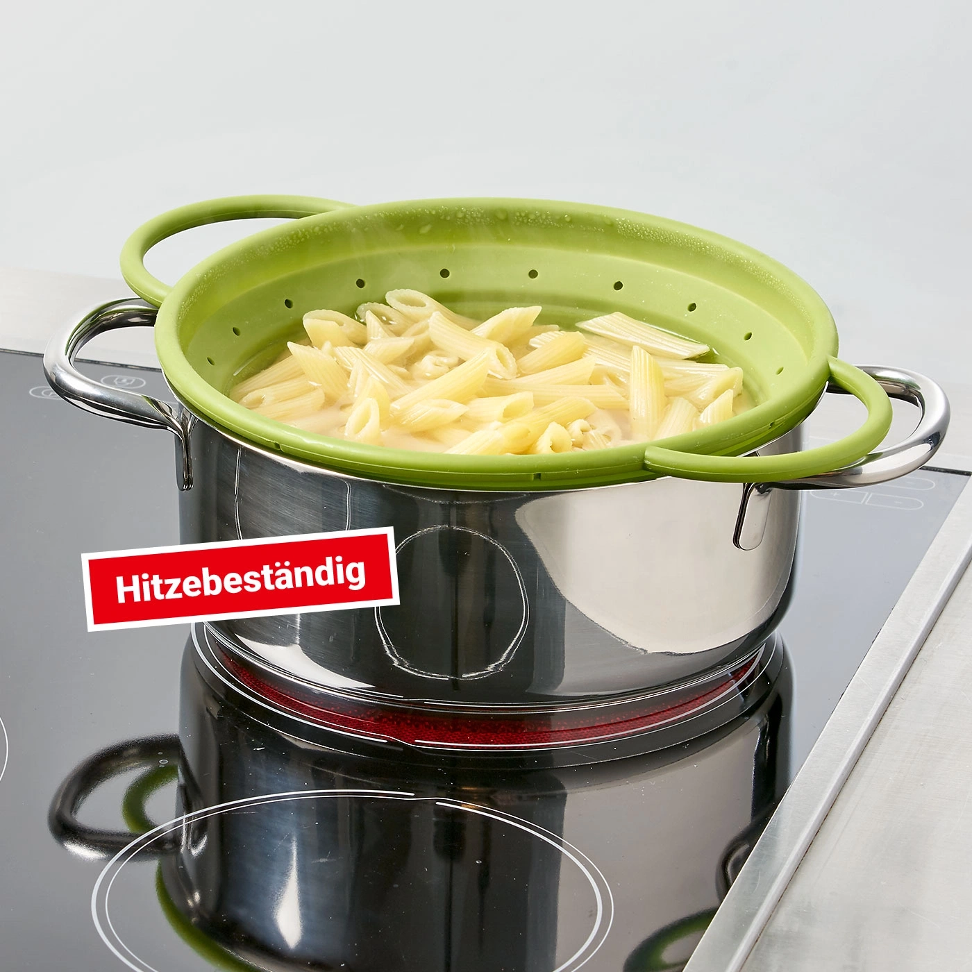 Topf mit Nudeln und hitzebeständigem Sieb auf Herdplatte