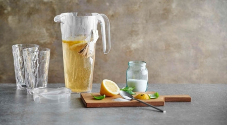 Boisson au citron avec ingrédients sur planche de bois et verres.