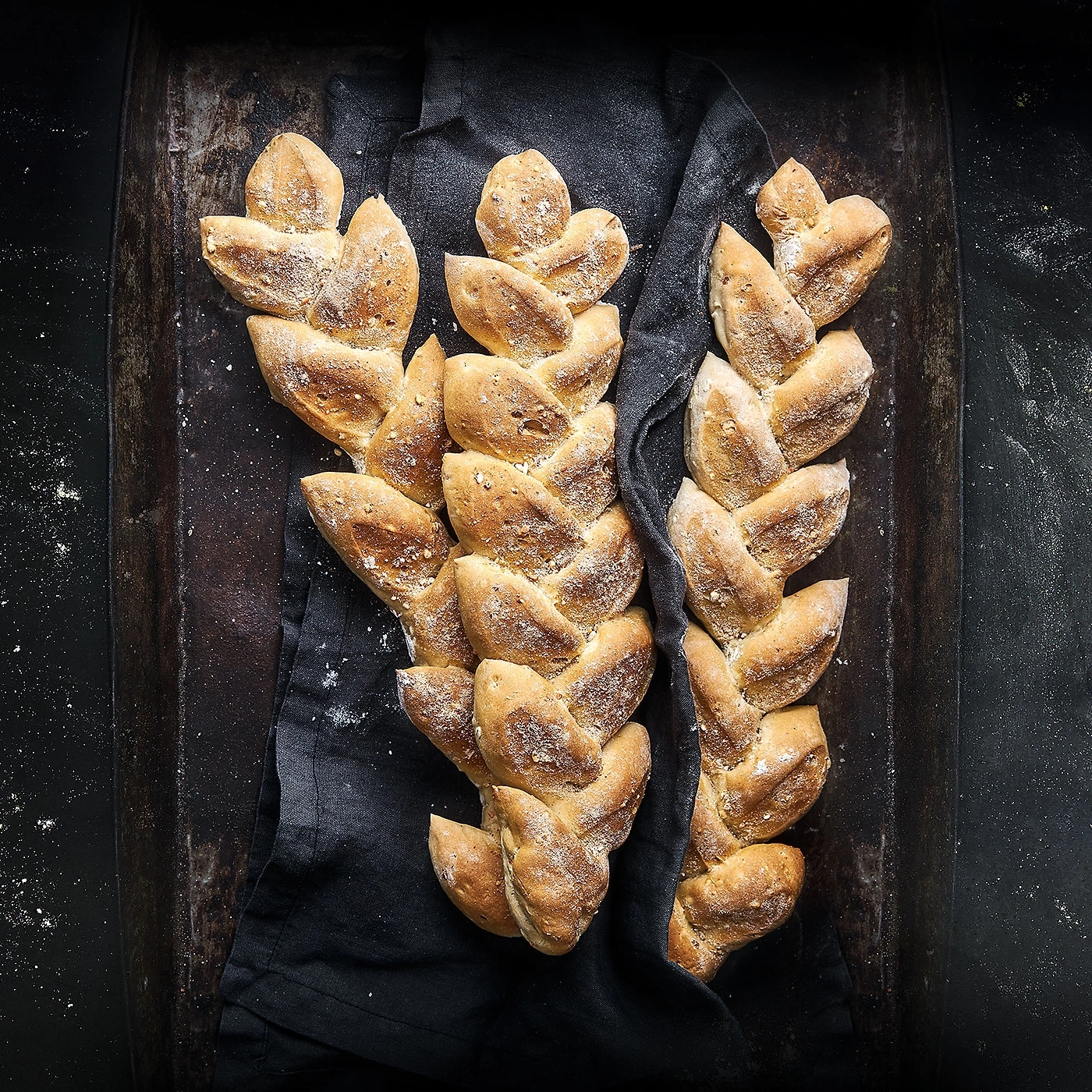 Pain tressé sur tissu noir, rustique et appétissant, arrangement de boulangerie