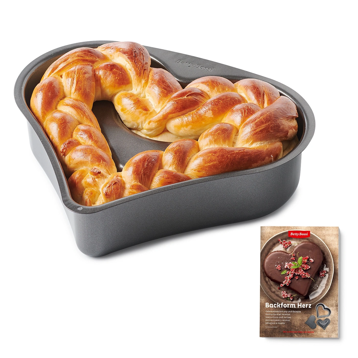 Herzförmige Backform mit Brot, daneben eine Broschüre mit Rezepten und Anleitungen.