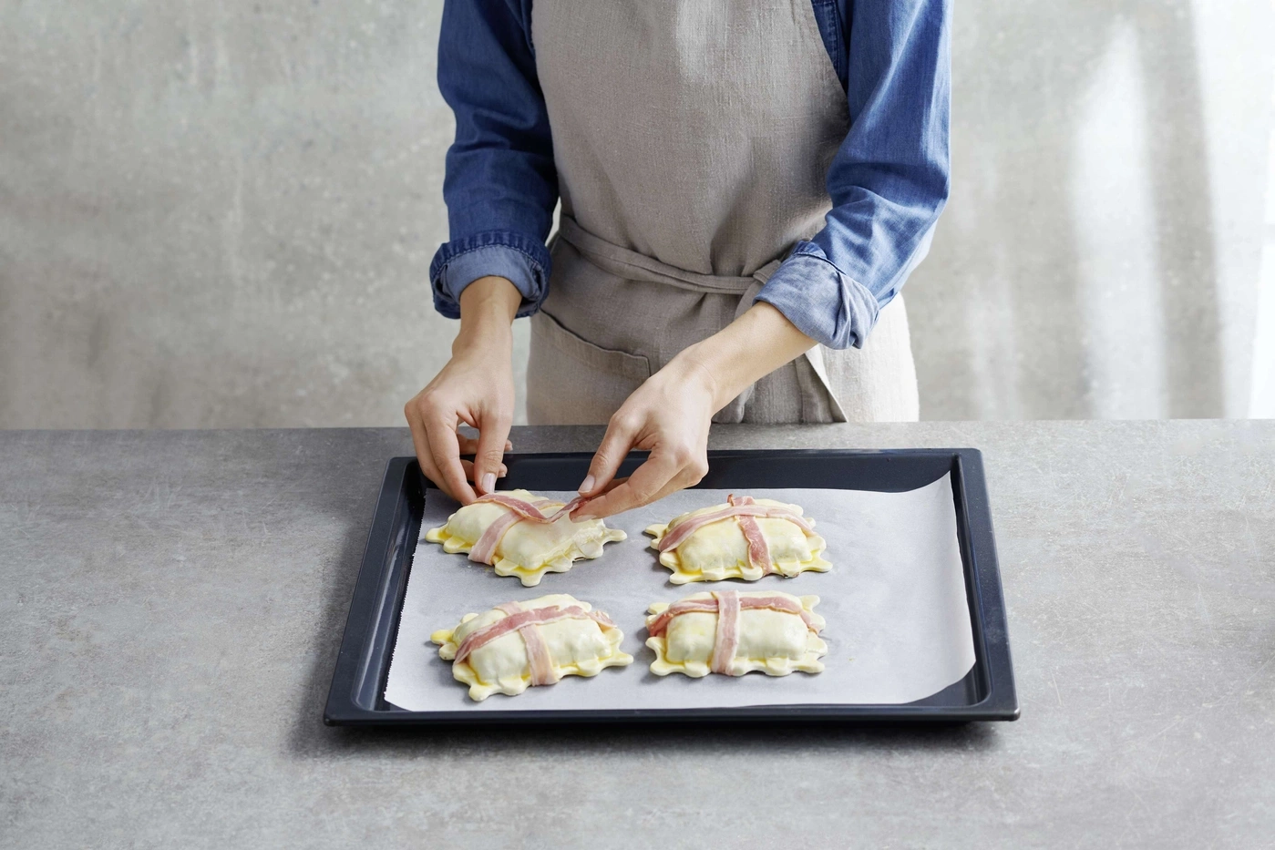 Personne pose du bacon sur des pâtisseries sur une plaque de cuisson. Cuisine.