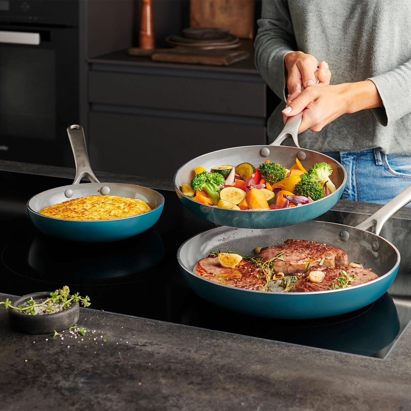 Trois poêles avec de la nourriture sur une cuisinière