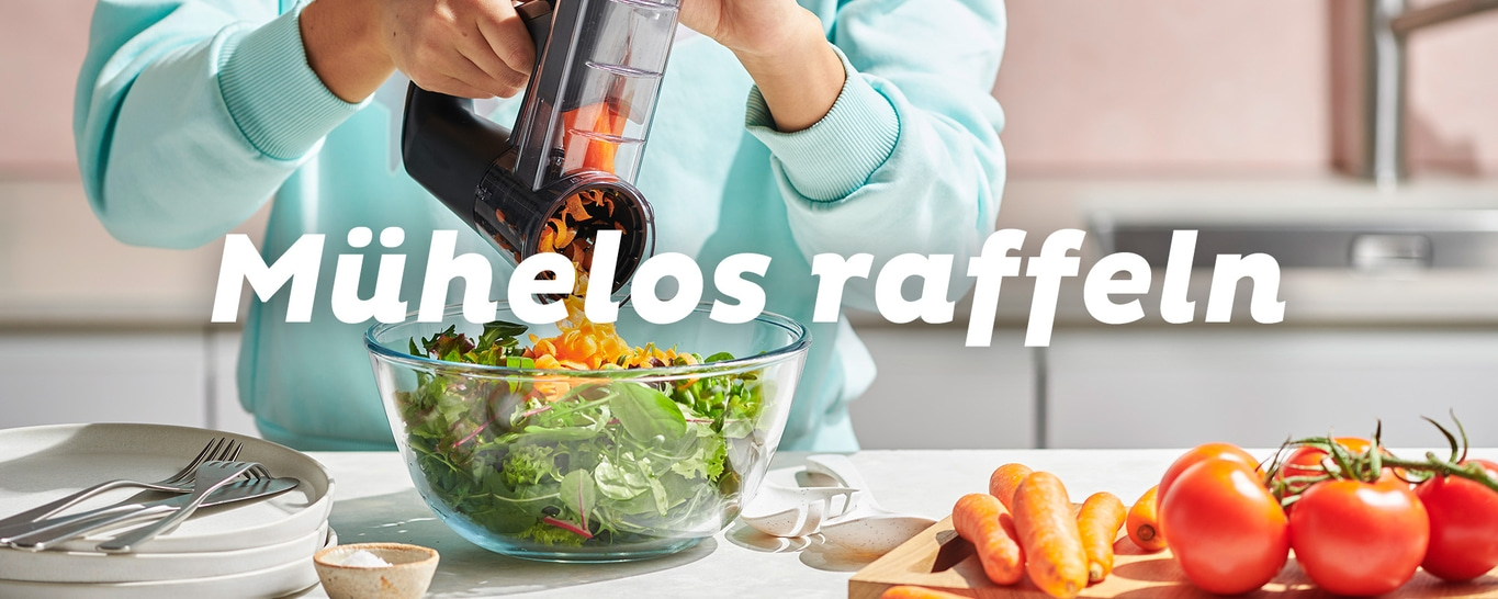 Mühelos raffeln: Karotten werden über einem Salat gerieben.